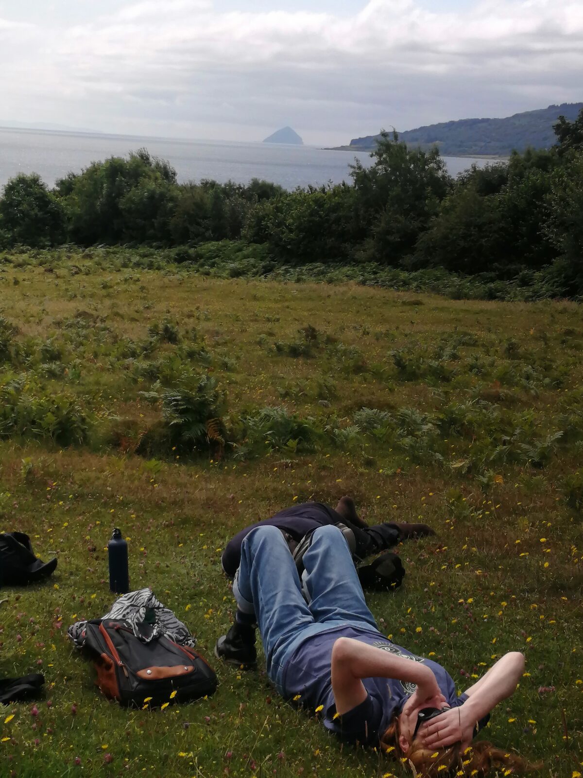 People resting in the grass overlooking the coast on Arran